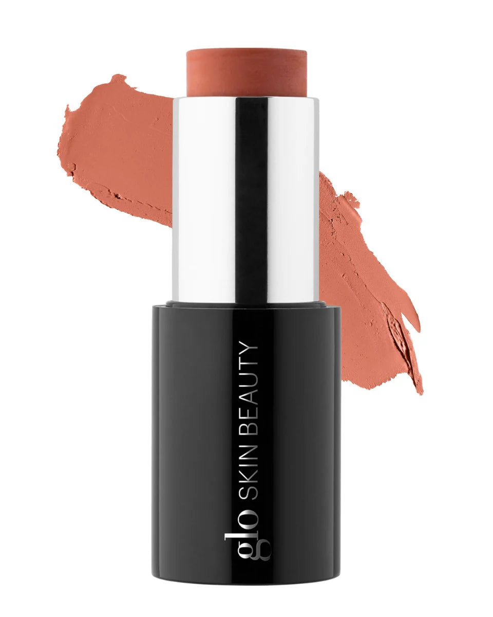 Glo Skin Beauty Cream Blush Stick in der Nuance Spark mit passendem Farb-Swatch im Hintergrund.