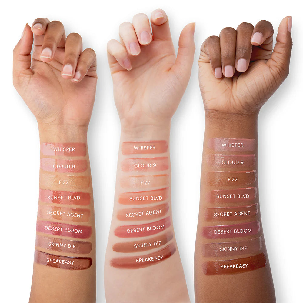 Drei Arme mit Lipgloss-Swatches in den Farbtönen Whisper, Cloud 9, Fizz, Sunset Blvd, Secret Agent, Desert Bloom, Skinny Dip und Speakeasy