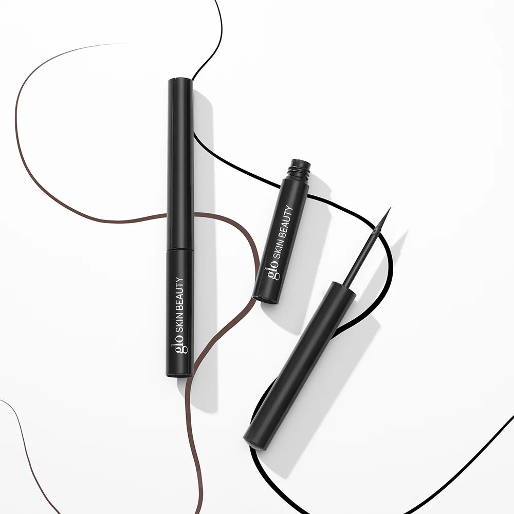 Zwei schwarze Glo Skin Beauty Liquid Eyeliner mit gezeichneten braunen und schwarzen Lidstrichen.