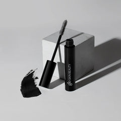 Glo Skin Beauty Mascara in schwarzer Tube mit separatem Bürstchen und schwarzem Farbswatch, Aufdruck Glo Skin Beauty auf der Verpackung.