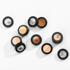 Runde schwarze Dual-Shade-Concealer-Kompakte mit Glo-Logo auf dem Deckel, in verschiedenen Hauttönen auf weißem Hintergrund