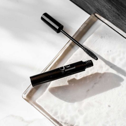 Glo Skin Beauty Mascara in schwarzer Tube mit geöffnetem Deckel und schmaler Bürste