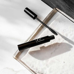 Glo Skin Beauty Mascara in schwarzer Tube mit geöffnetem Deckel und schmaler Bürste